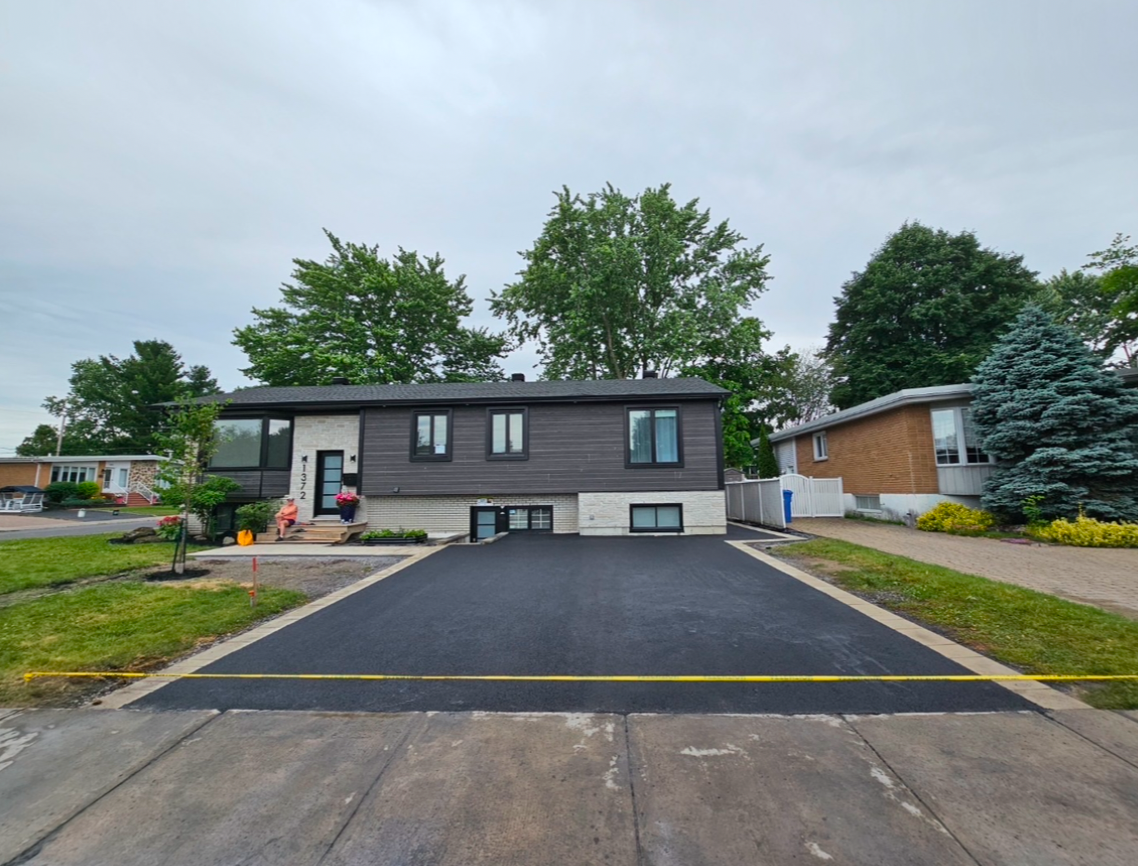Une maison avec une nouvelle allée asphaltée devant elle.