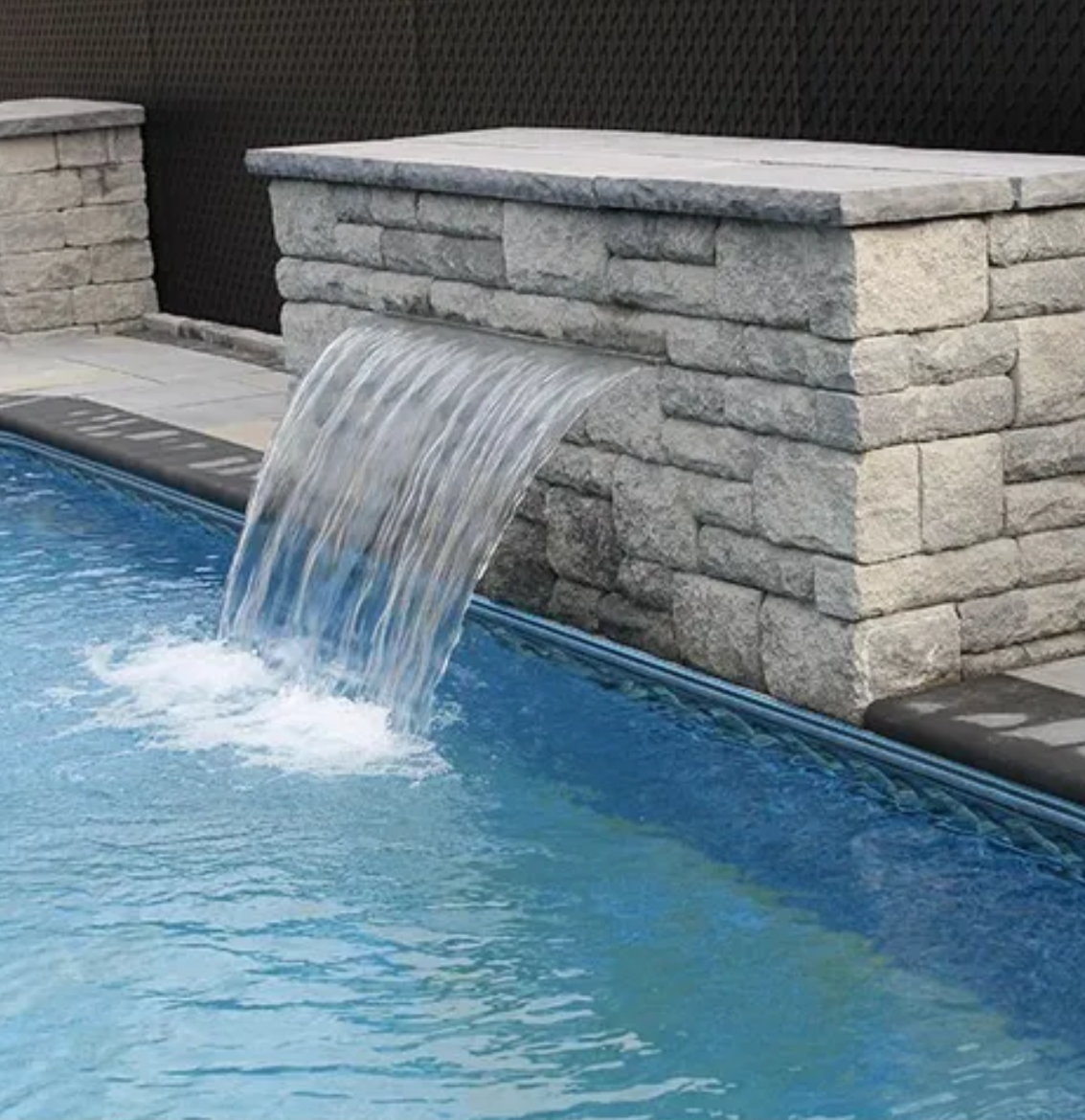 Une cascade sort d'un mur de briques dans une piscine.
