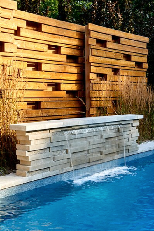 Une piscine avec une cascade derrière une clôture en bois