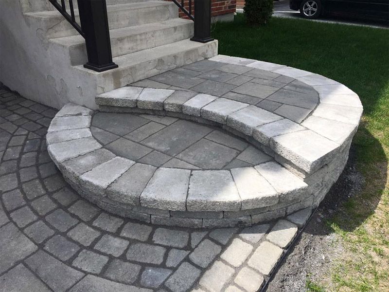 Une allée circulaire en pierre avec des marches menant à une maison.