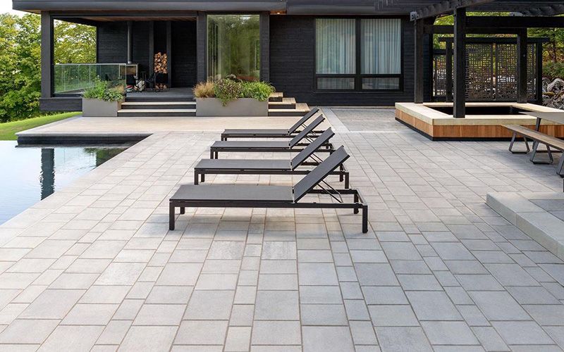 Une rangée de chaises longues est alignée sur un patio devant une maison.