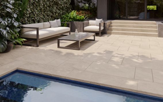 Un patio avec un canapé et des chaises à côté d'une piscine.