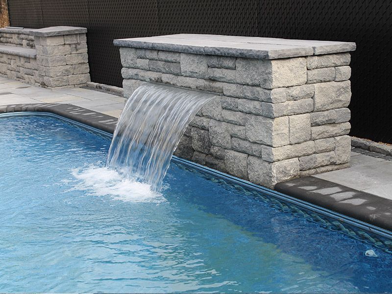 Une cascade sort d'un mur de briques dans une piscine.
