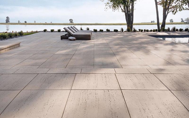 Un patio avec des chaises et une piscine en arrière-plan