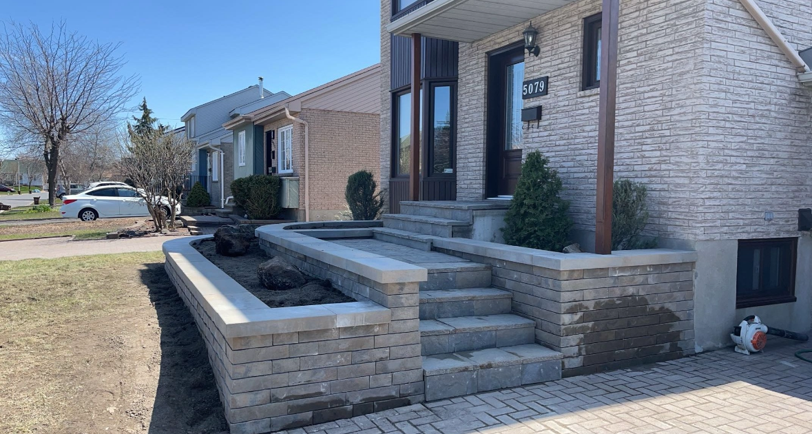 Une maison en briques blanches avec des escaliers et une jardinière devant.