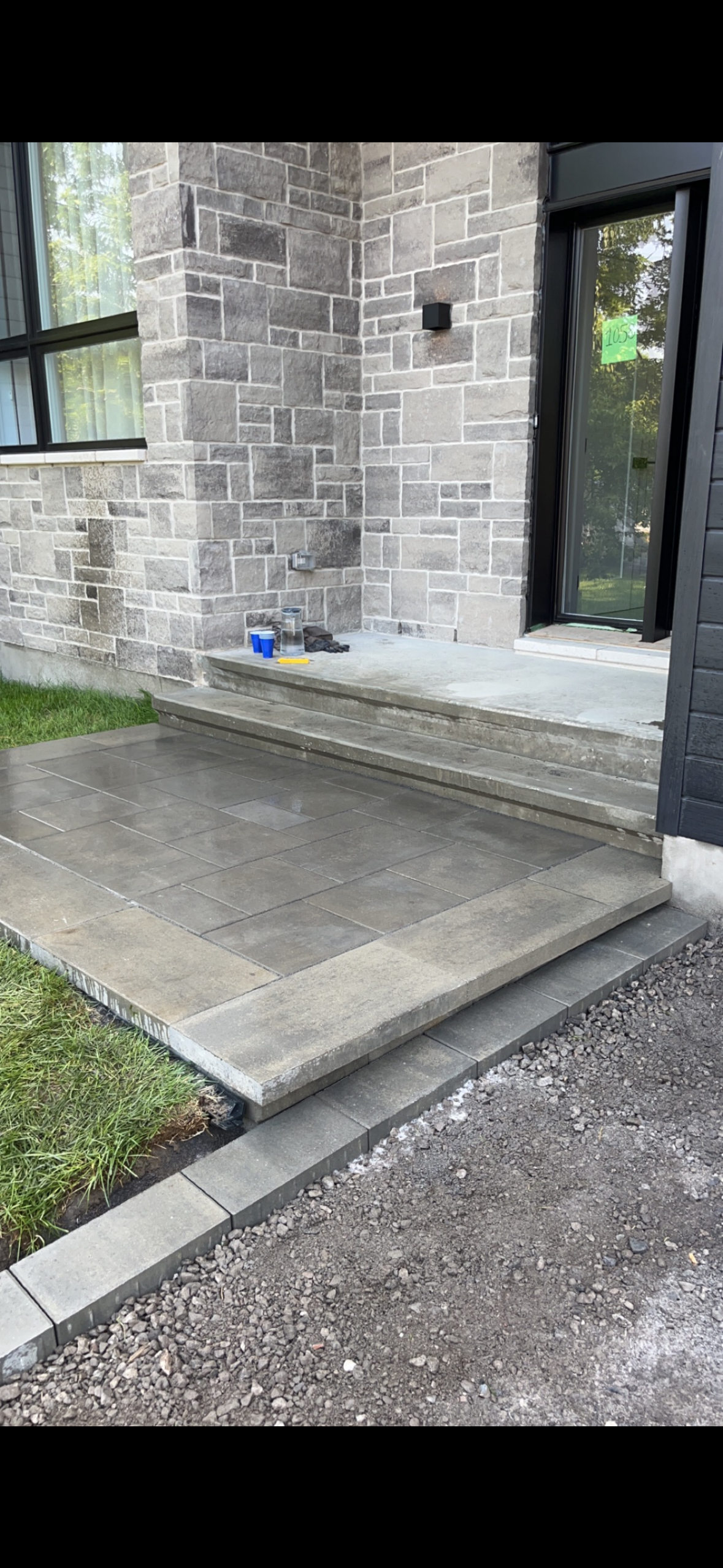 Une passerelle en béton est en cours de construction devant une maison en briques.