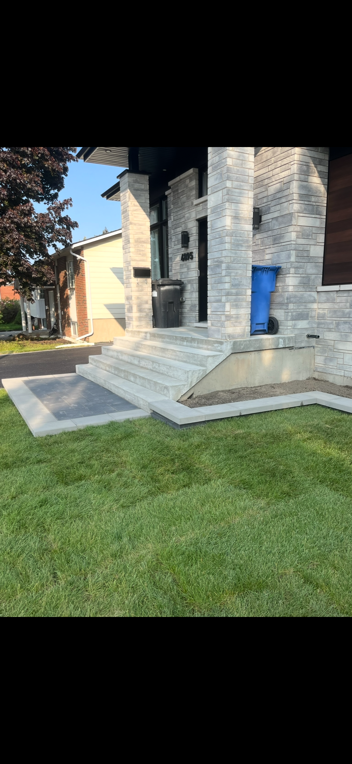 Une maison avec une poubelle bleue devant.