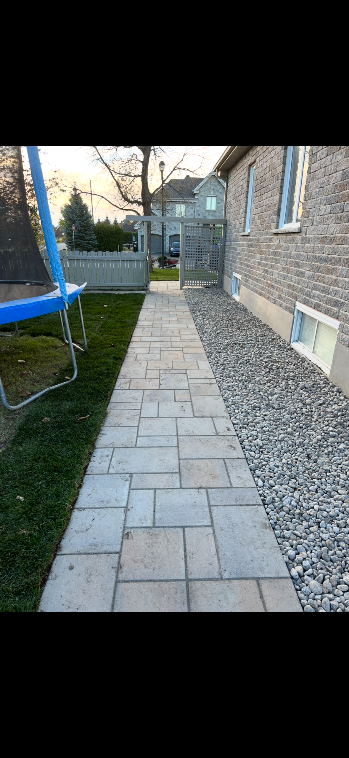 Un trottoir menant à une maison avec un trampoline dans l'arrière-cour.