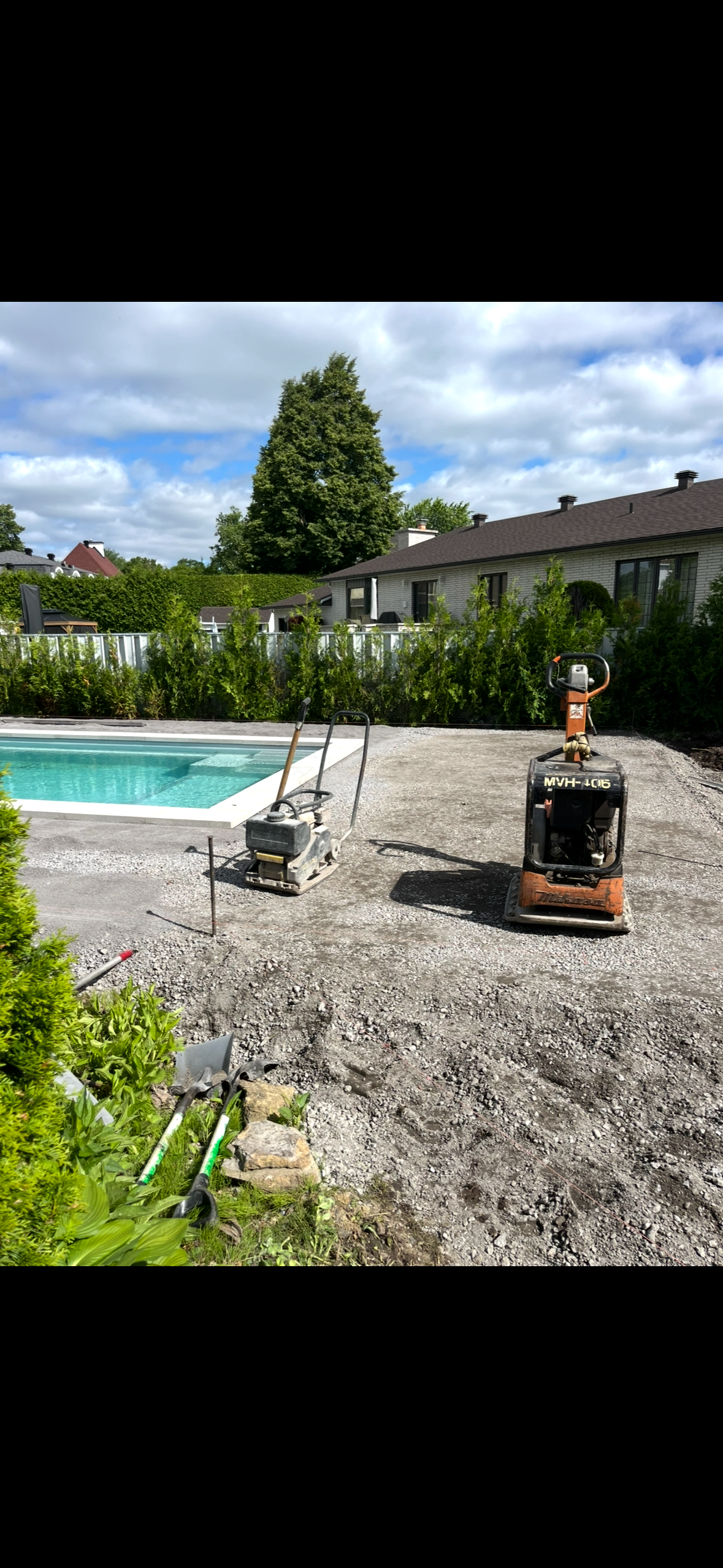 Une petite machine est posée sur un tas de gravier à côté d'une piscine.