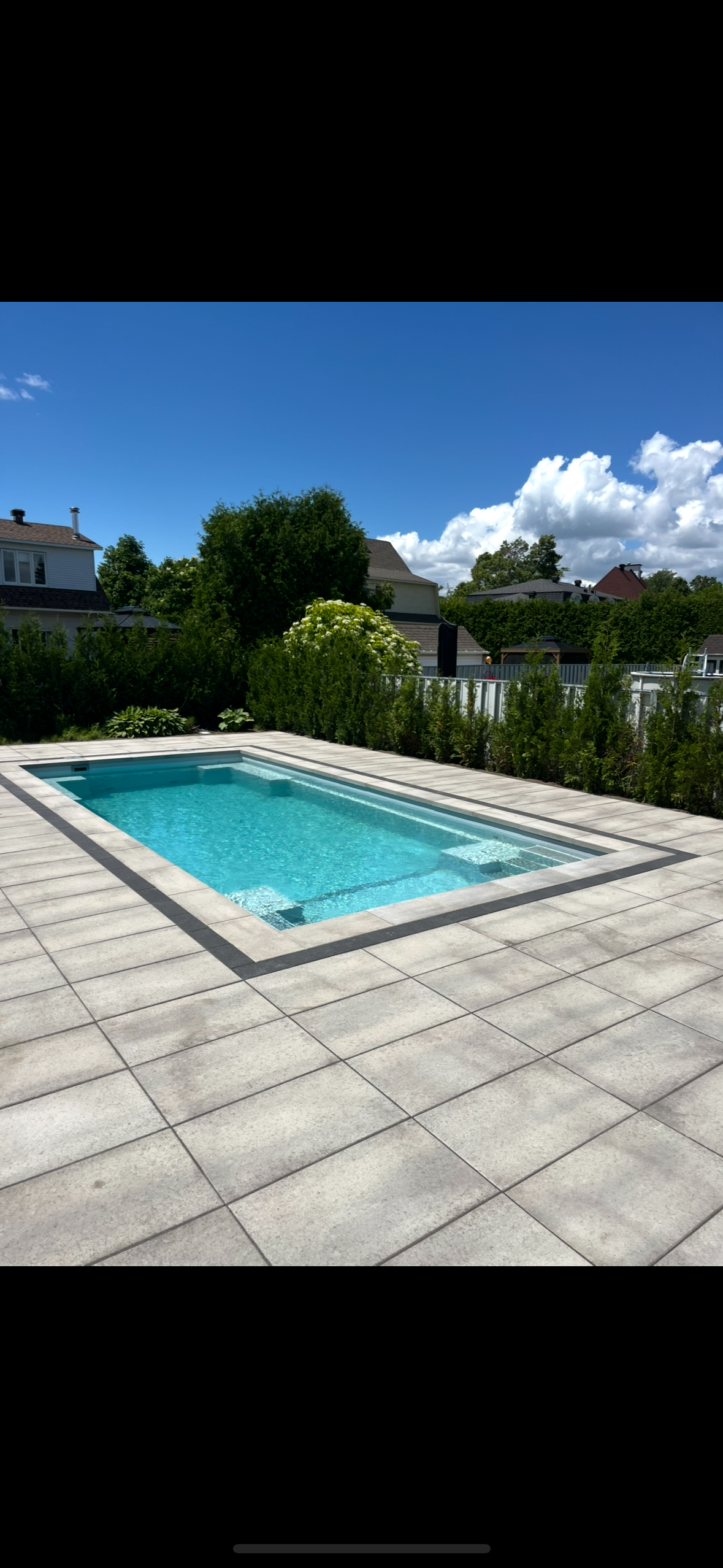 Une grande piscine est située au sommet d'un patio carrelé.