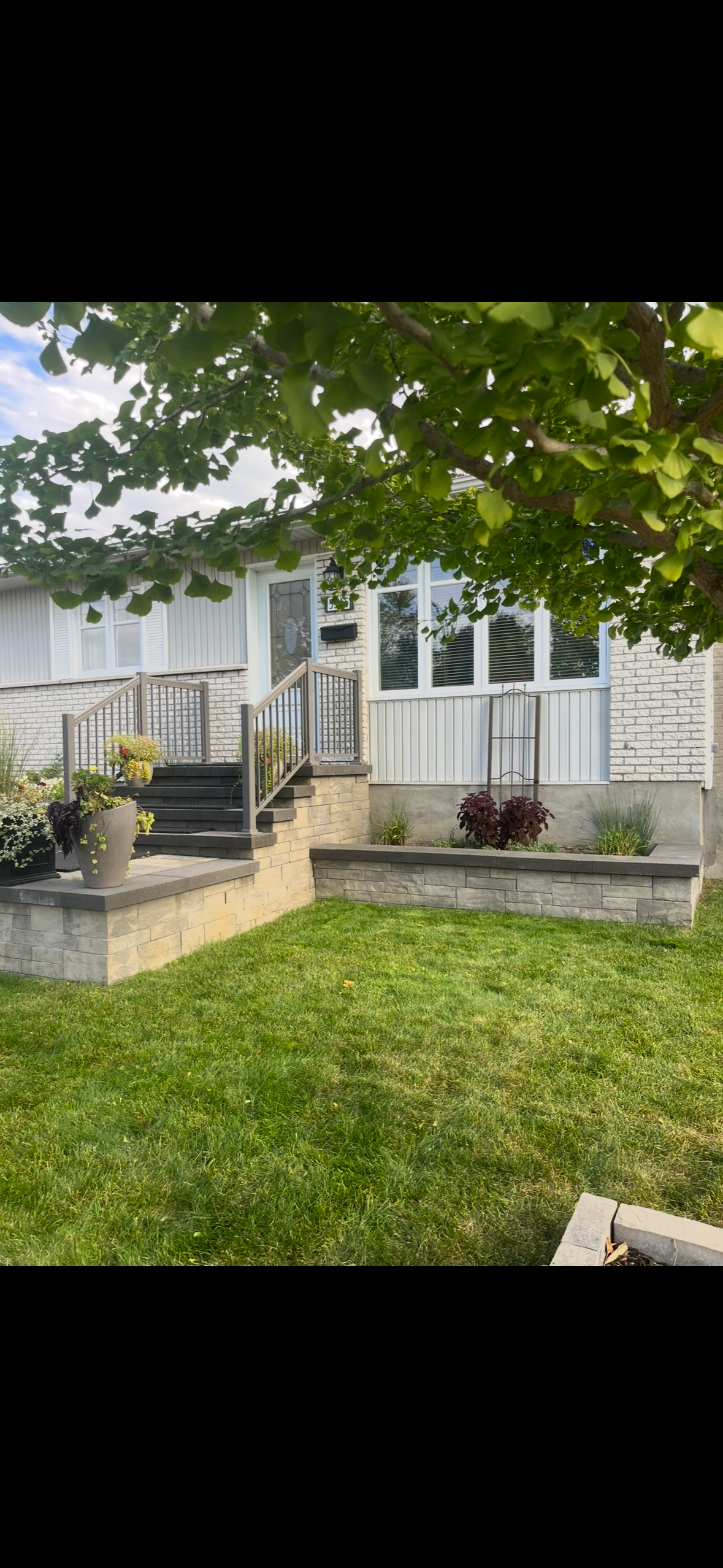 Une maison blanche avec une pelouse verte luxuriante et des escaliers devant elle.