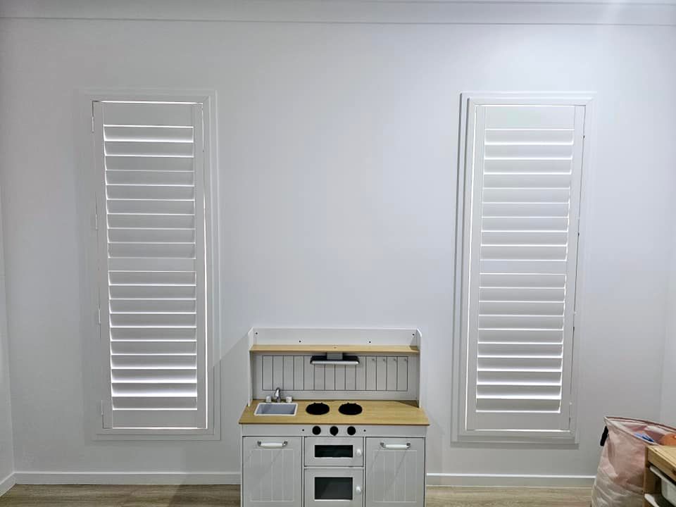 A Close Up Of A Row Of White Shutters On A Window — Modern Window Furnishings In Woodgate, QLD