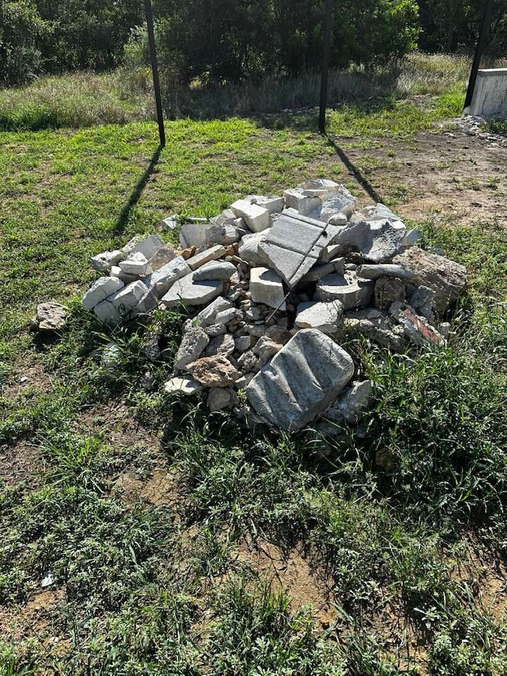 A pile of rocks is sitting in the middle of a grassy field.