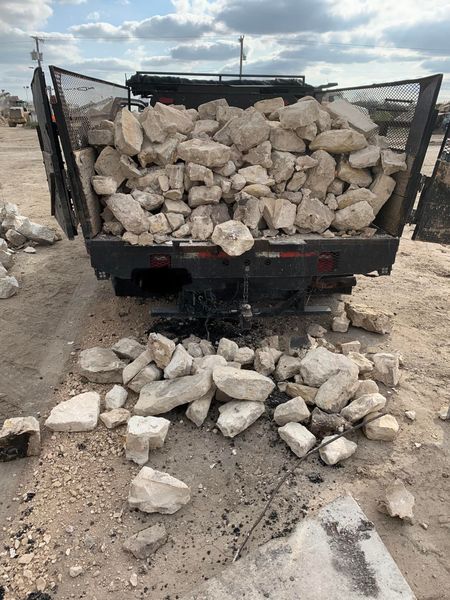 A truck filled with rocks is sitting in the dirt.