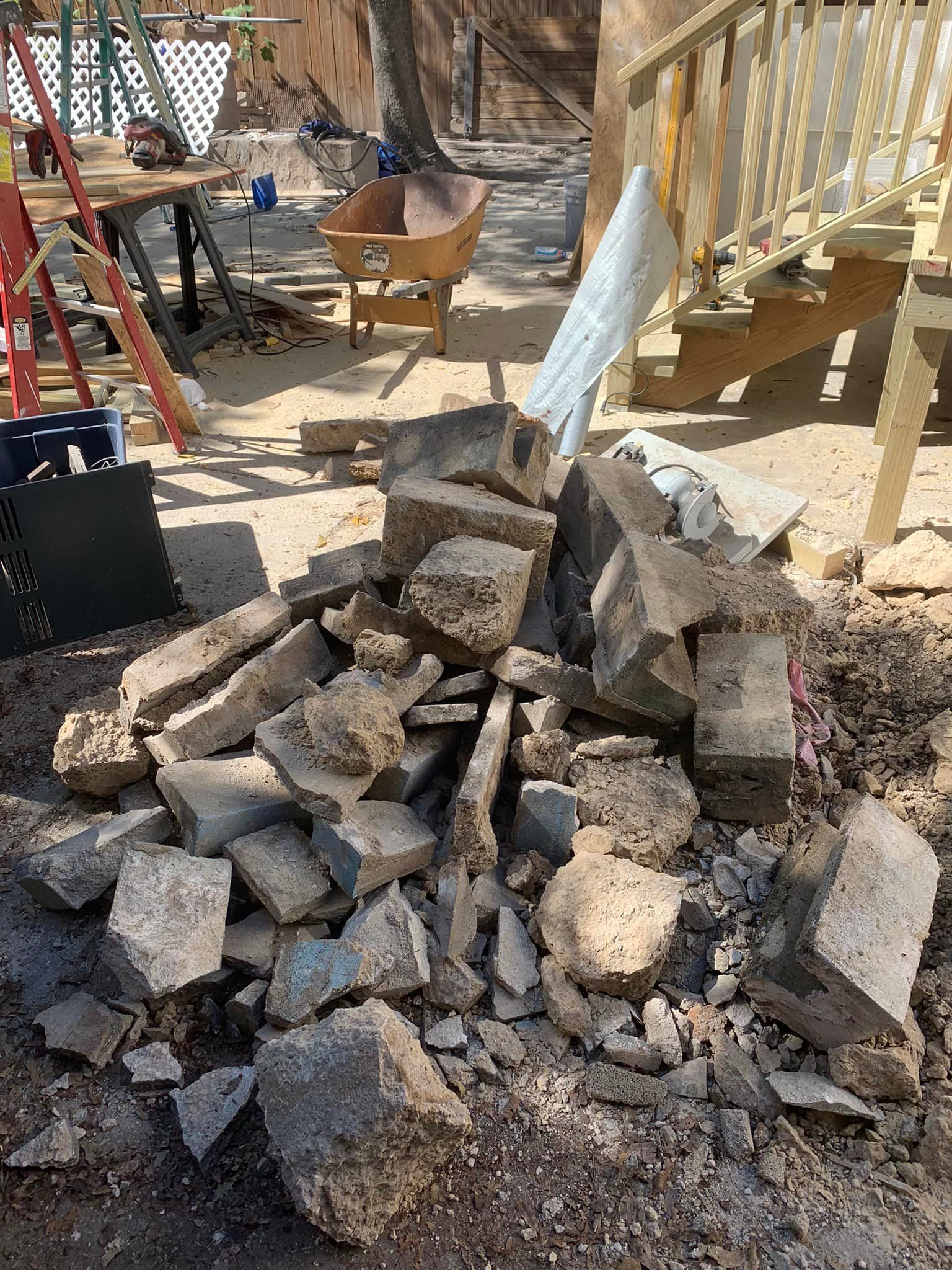 A pile of rocks is sitting on the ground next to a wheelbarrow.