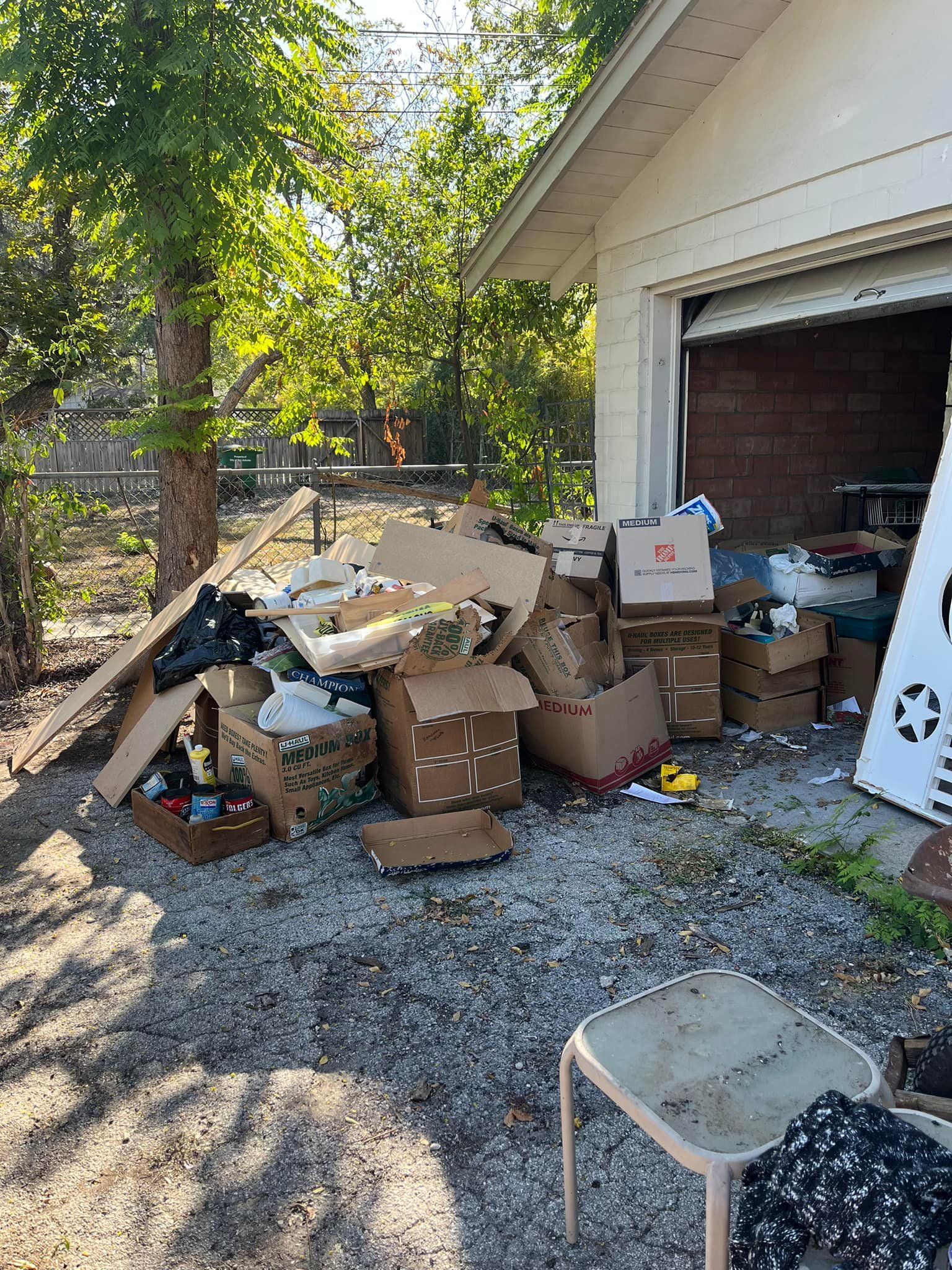 A pile of cardboard boxes is sitting in front of a garage.