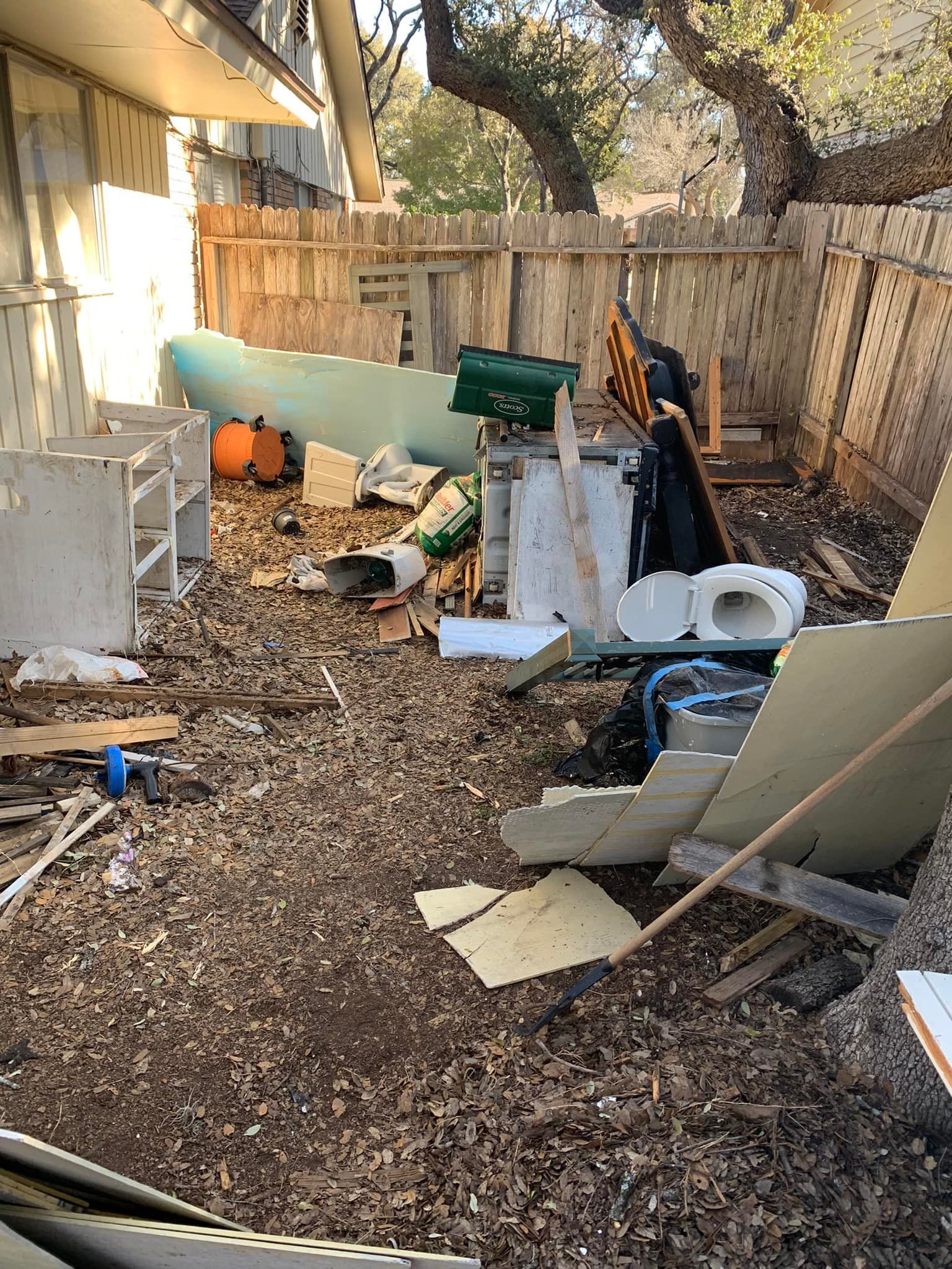 There is a lot of trash in the backyard of a house.