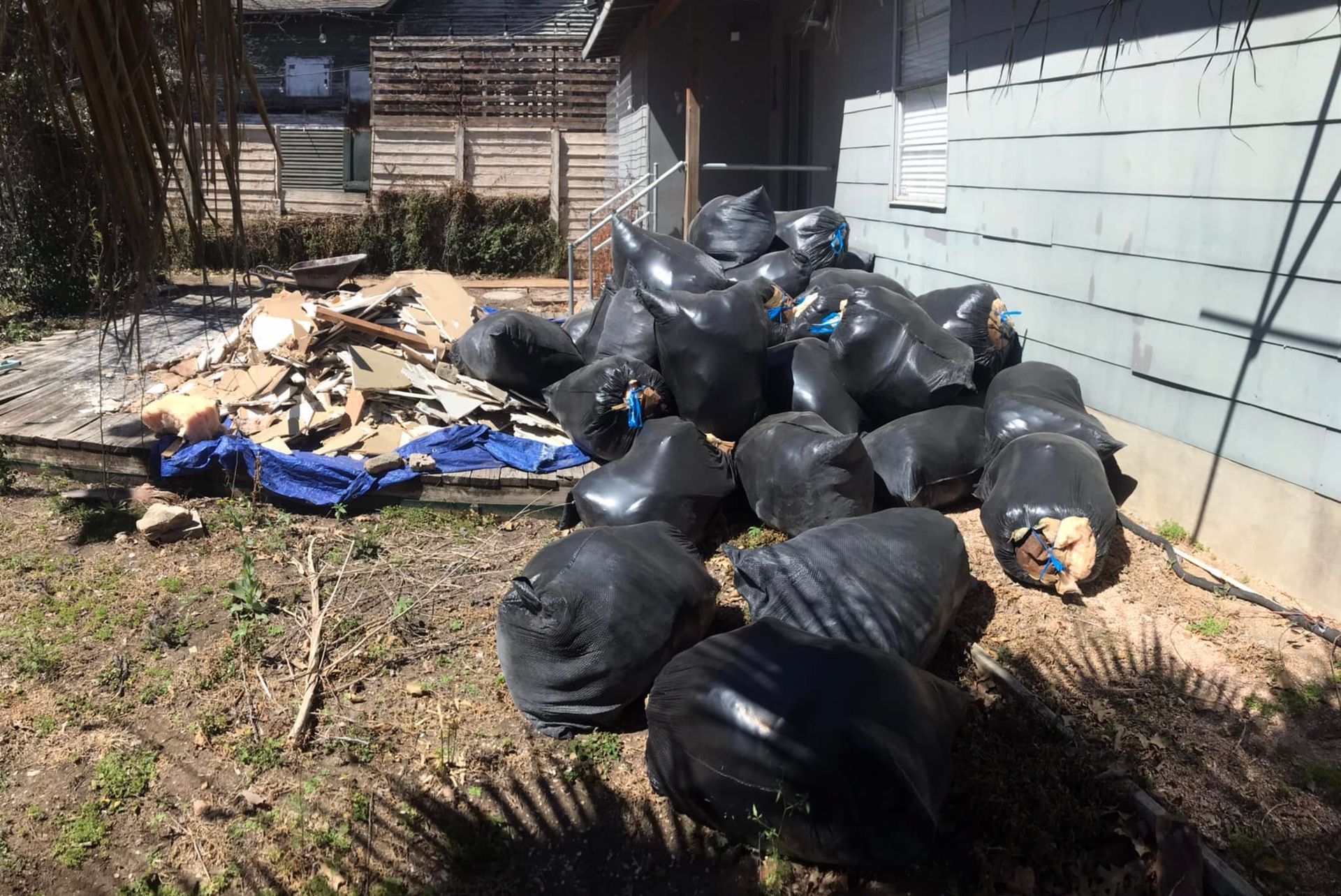 A pile of trash bags is sitting in front of a house.