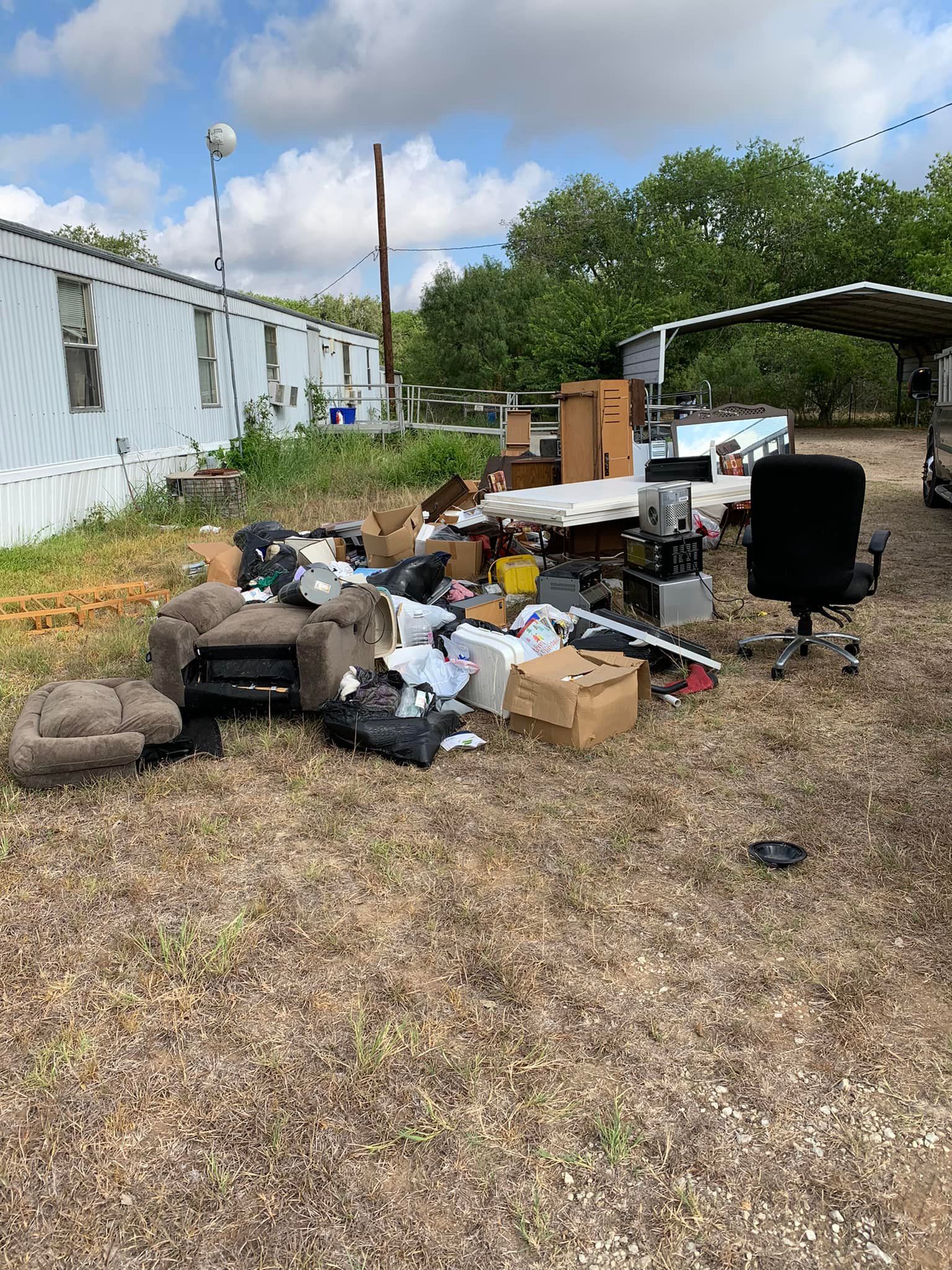 A pile of trash is sitting in the middle of a field.