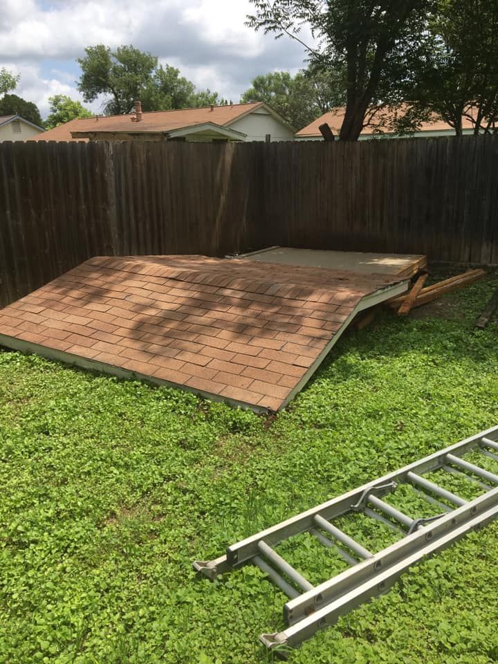 A ladder is sitting in the grass next to a broken roof.