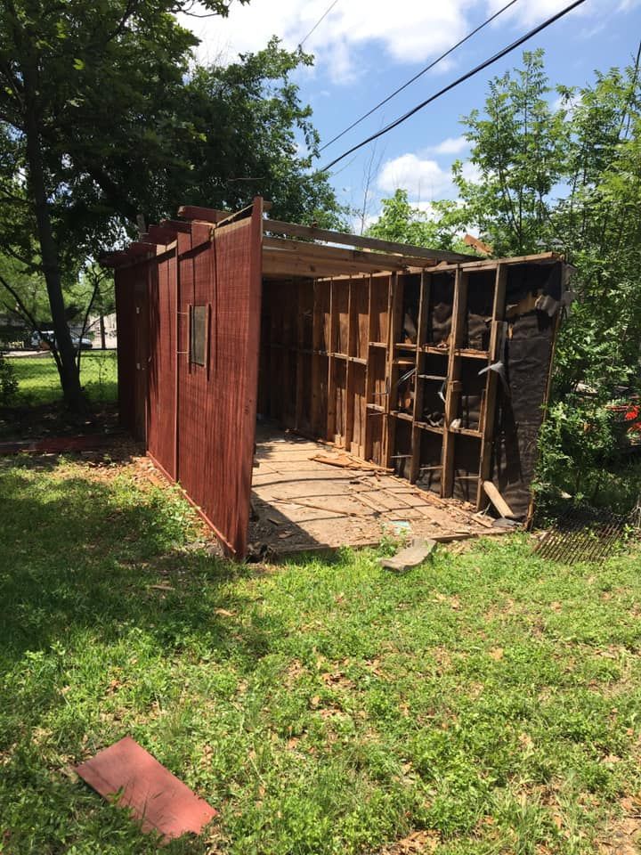 A red shed is being demolished in a grassy yard