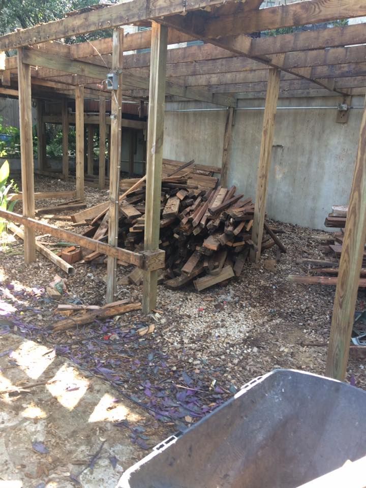 A pile of wood is sitting under a wooden structure.