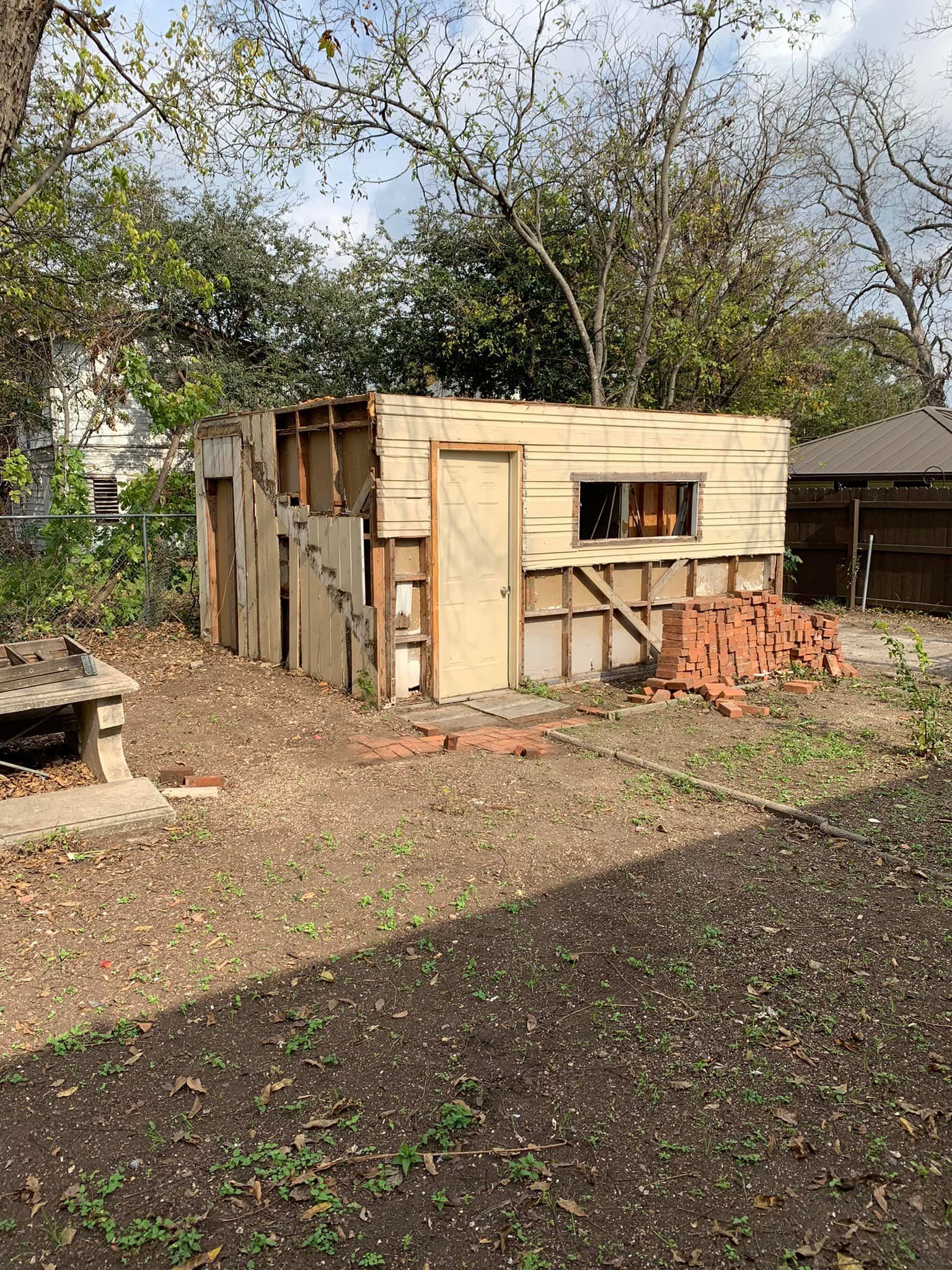 A wooden shed is being demolished in a backyard.