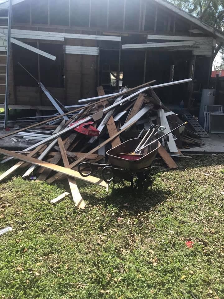 A wheelbarrow is sitting in front of a pile of wood.
