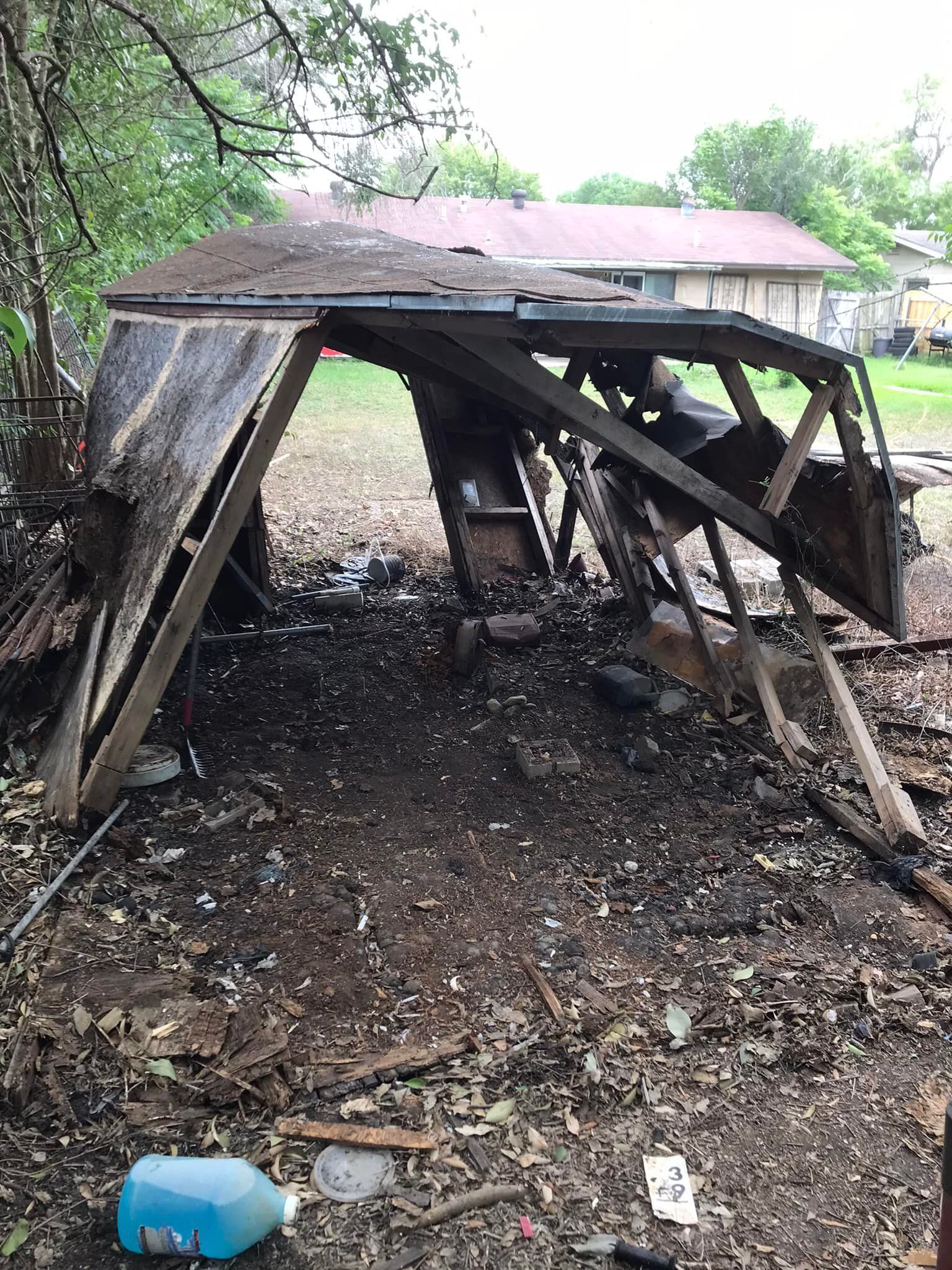 A wooden structure is sitting in the dirt in front of a house.