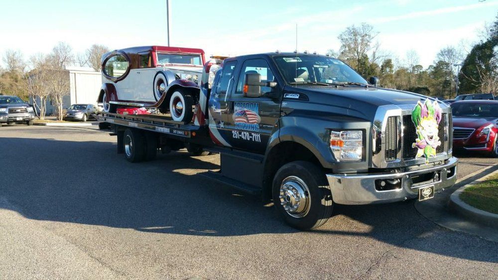 A tow truck is carrying a car on the back of it.