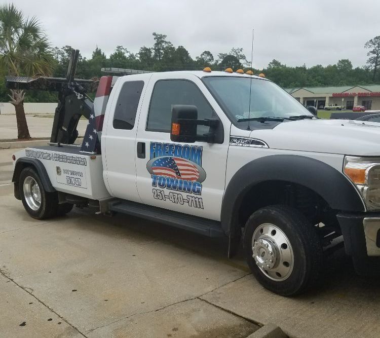 A white tow truck with american towing written on the side