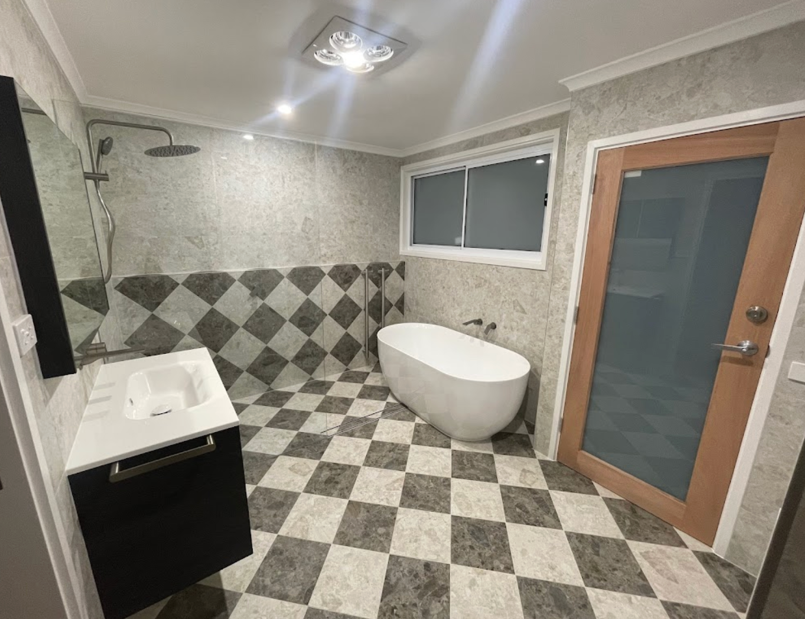 A bathroom with a bathtub , sink , mirror and checkered floor.
