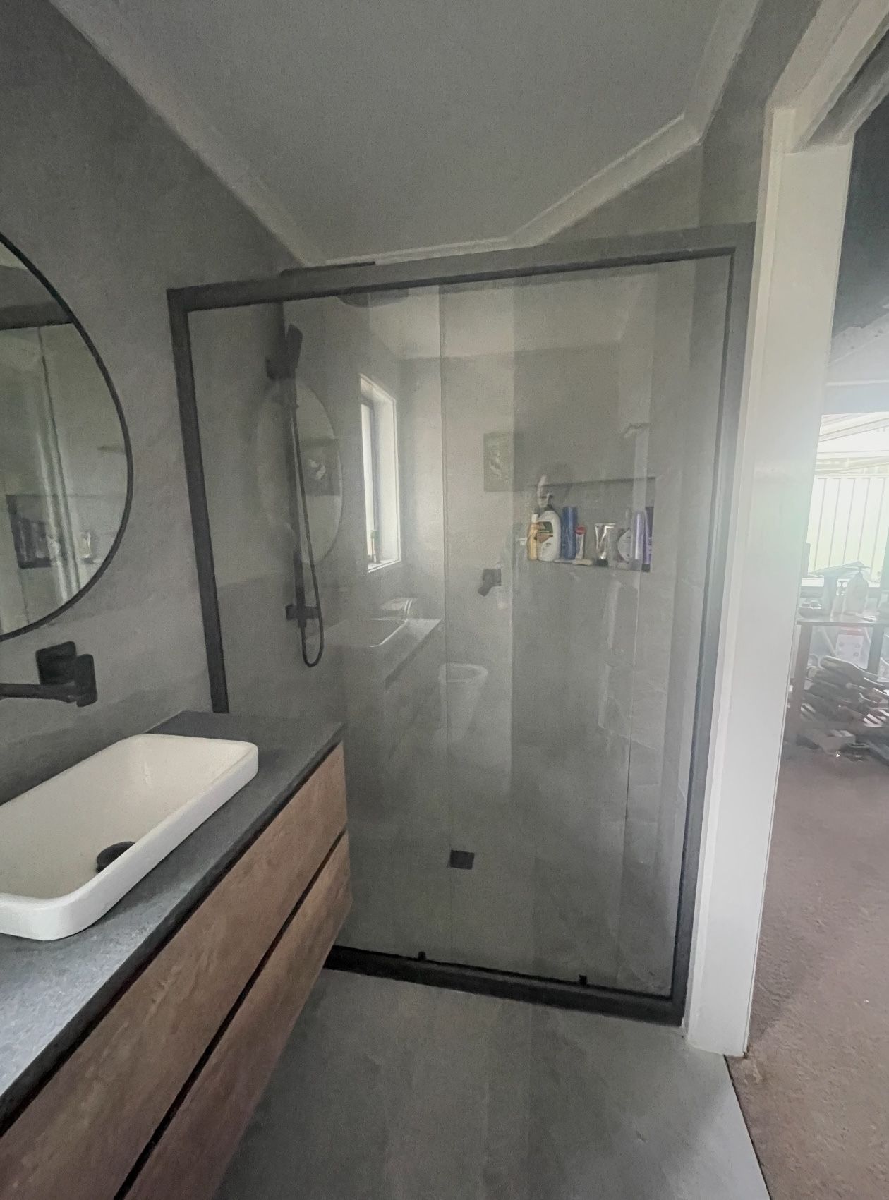 A bathroom with a sink , mirror and shower stall.