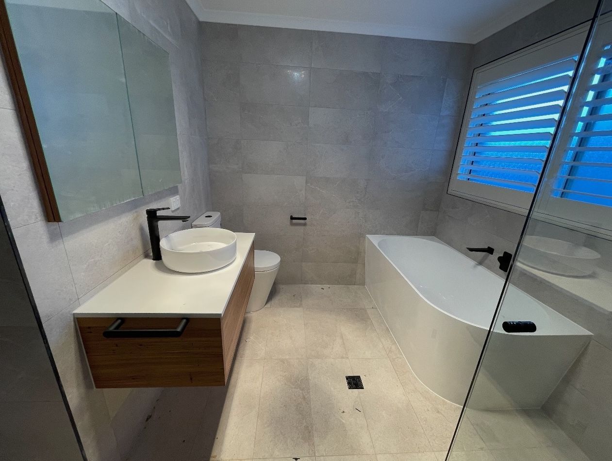 A bathroom with a tub , sink , toilet and mirror.