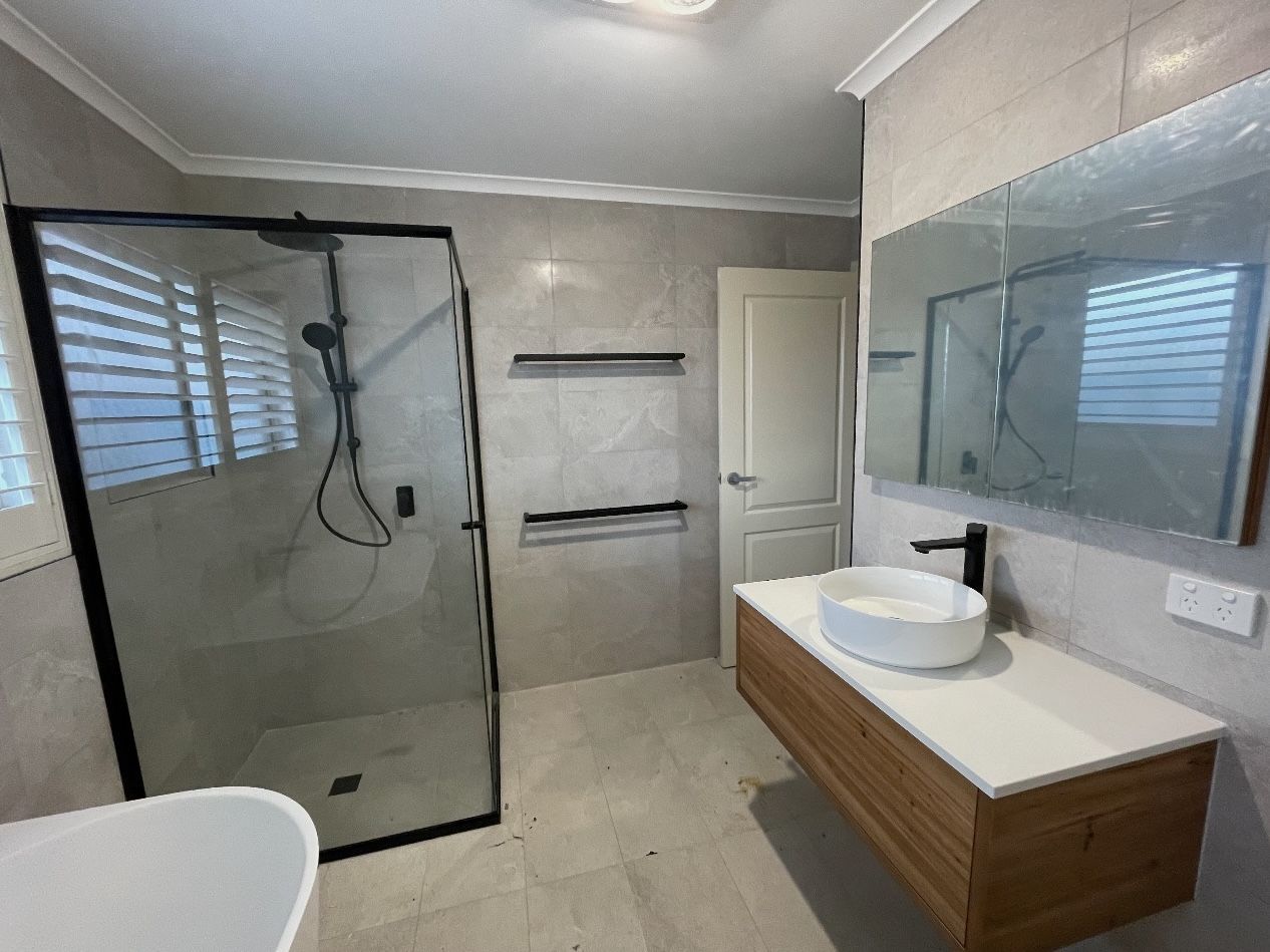 A bathroom with a sink , shower and mirror.