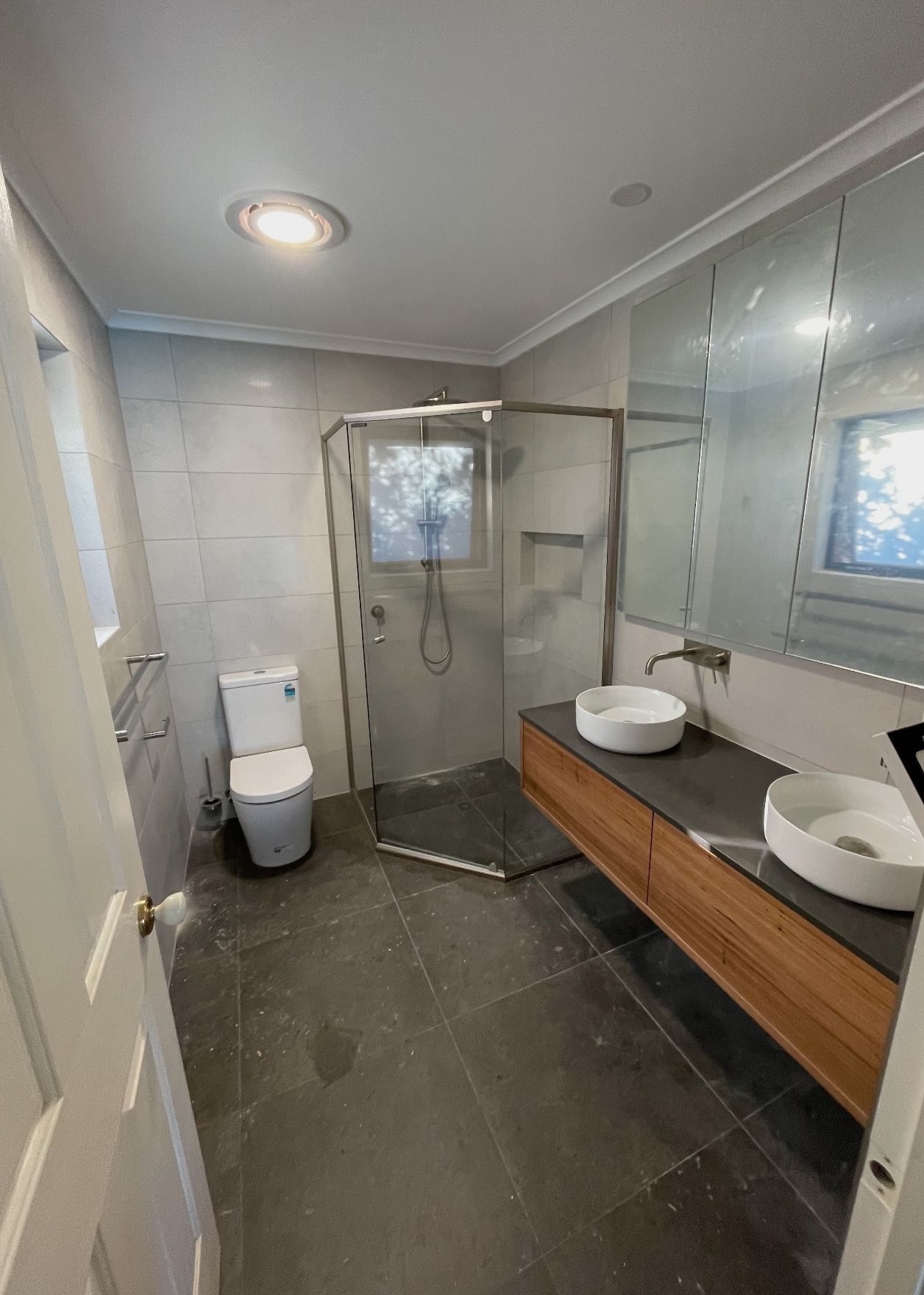 A bathroom with a toilet , sink , shower and mirror.