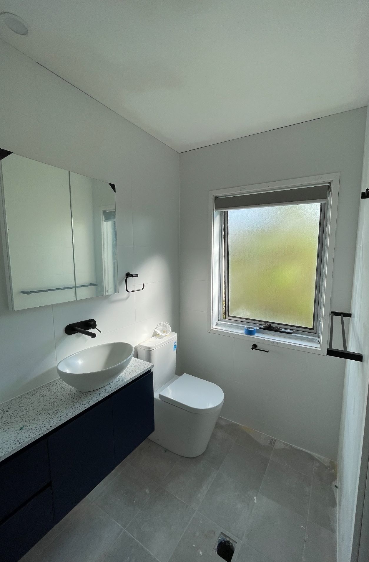 A bathroom with a sink , toilet , mirror and window.