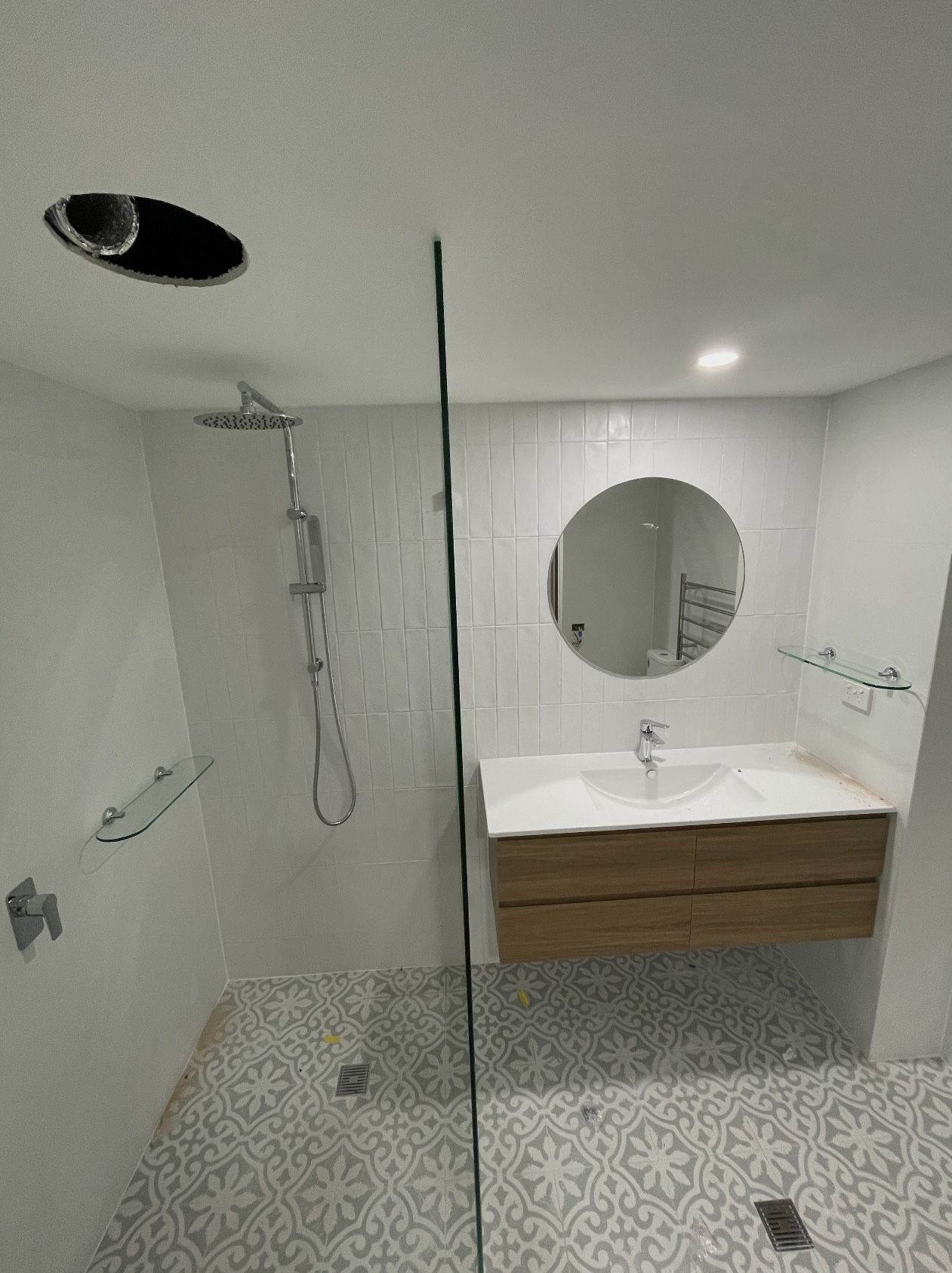 A bathroom with a walk in shower , sink and mirror.