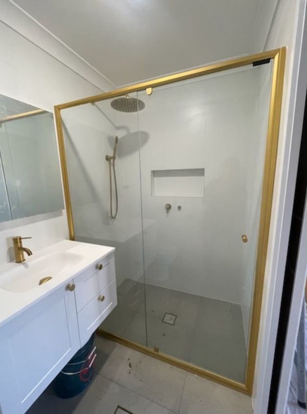 A bathroom with gold detailing and features, shower and sink