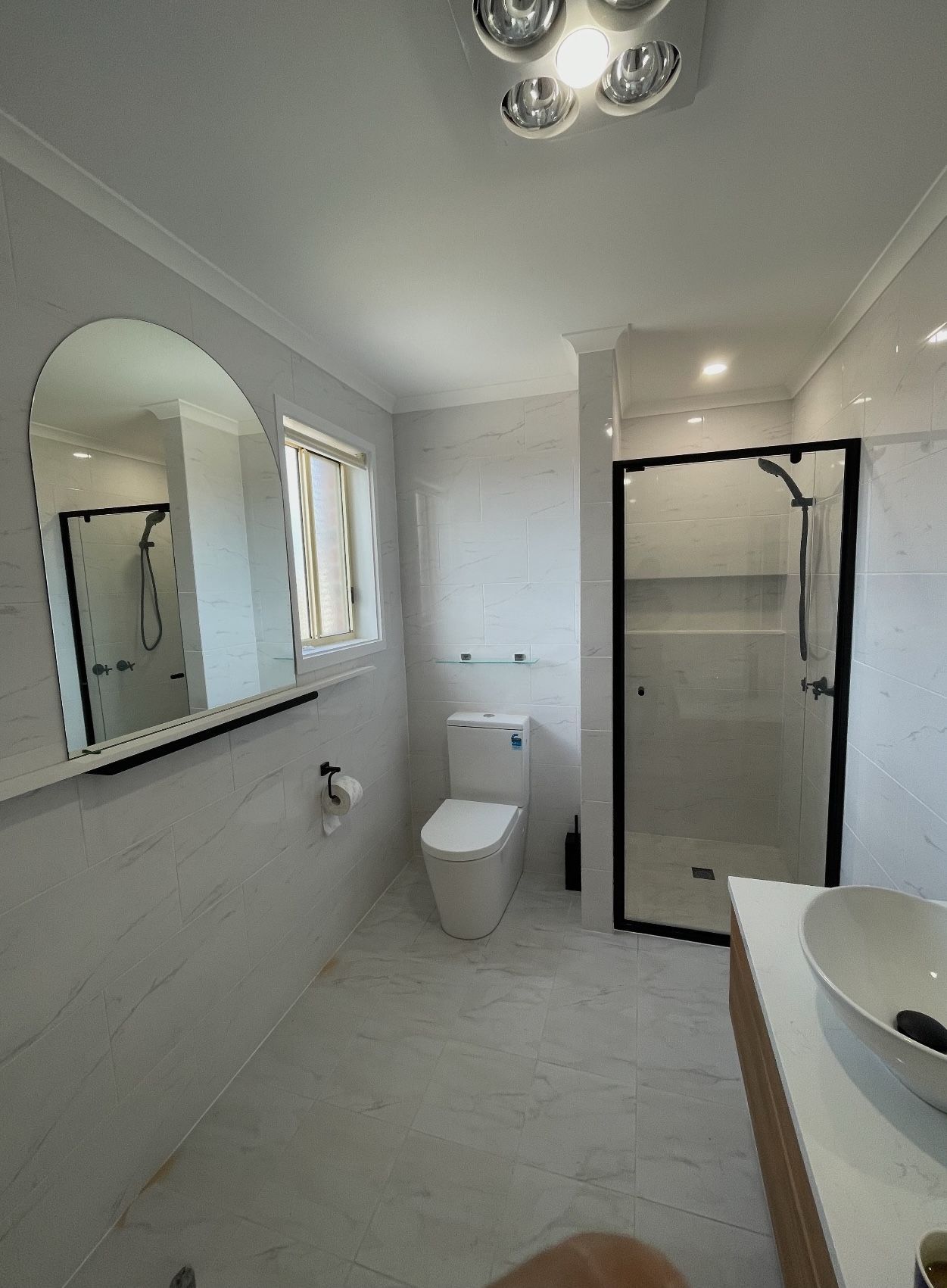 A bathroom with a toilet , sink , shower and mirror.