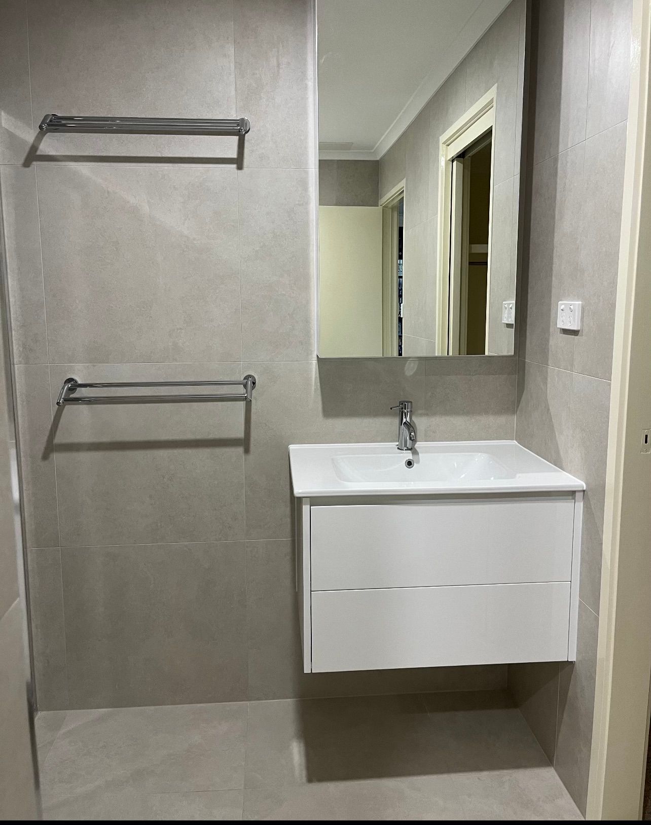 A bathroom with a sink , mirror and towel rack.