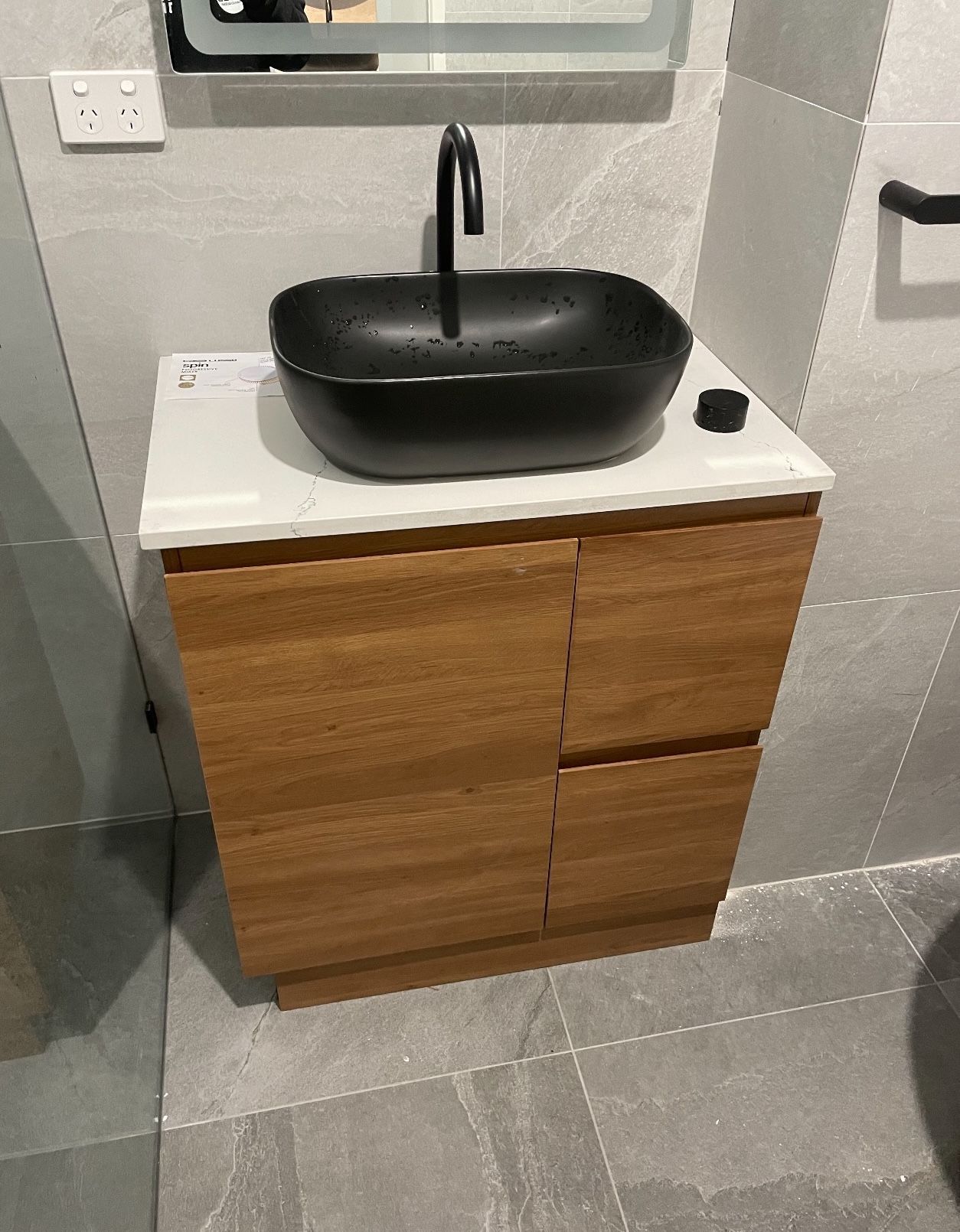 A black sink is sitting on top of a wooden vanity in a bathroom.