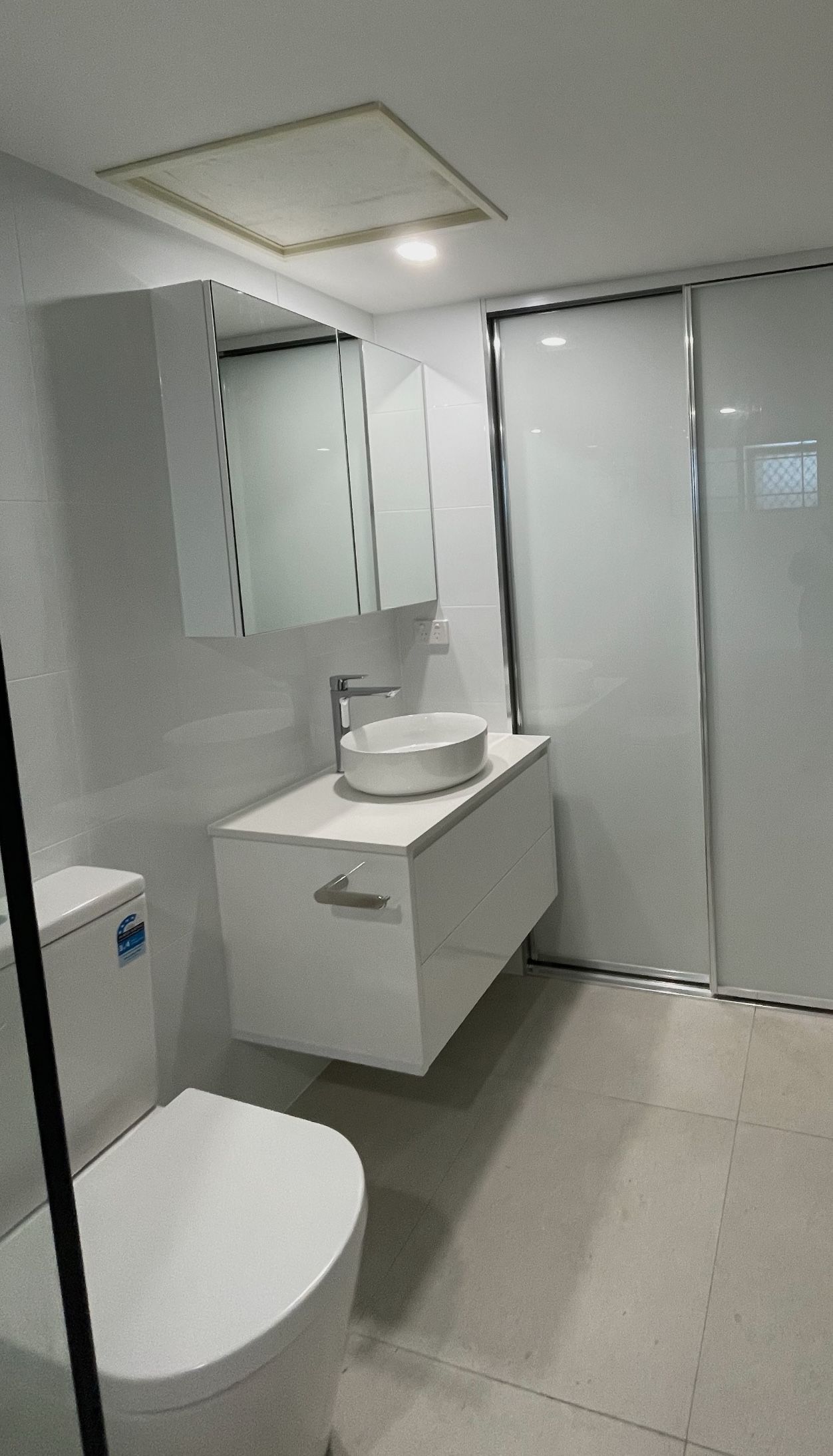 A bathroom with a toilet , sink and mirror.