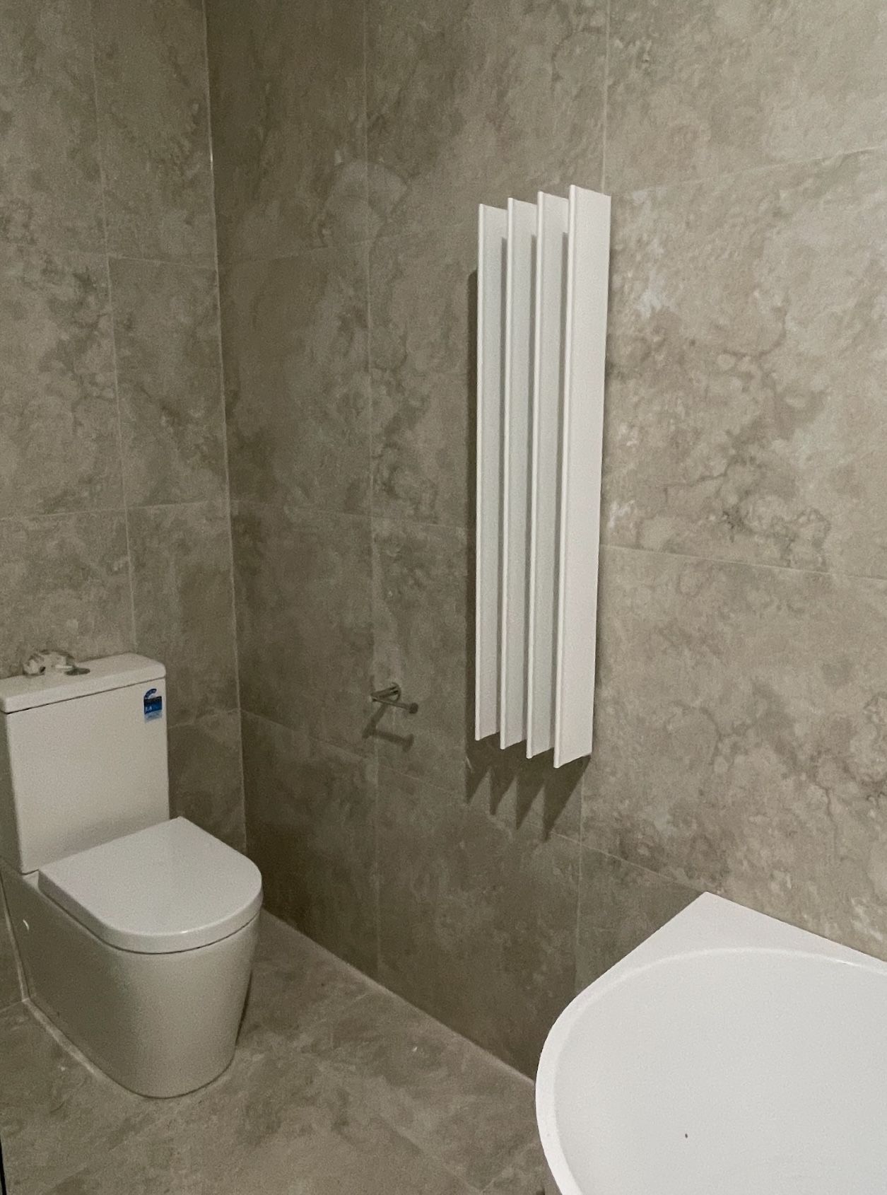 A bathroom with a toilet , sink , and radiator.