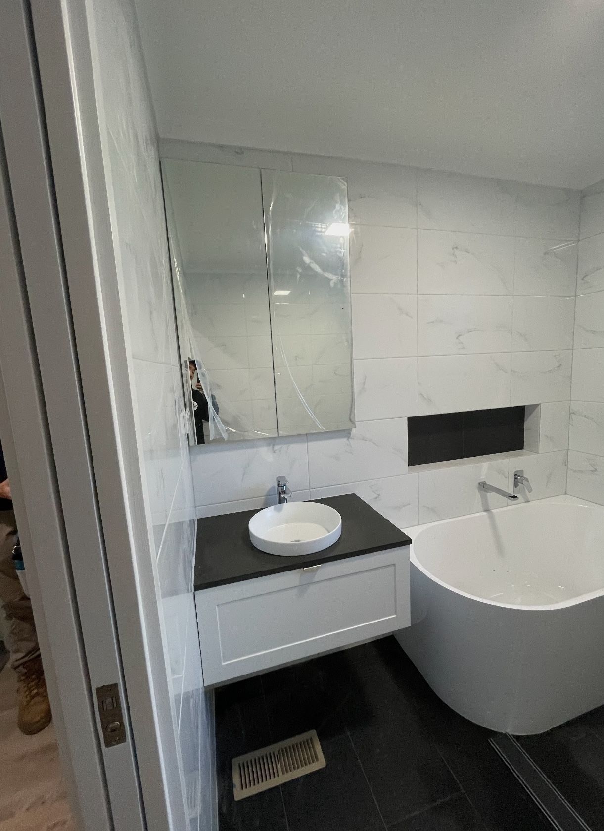 A bathroom with a bathtub , sink and mirror.