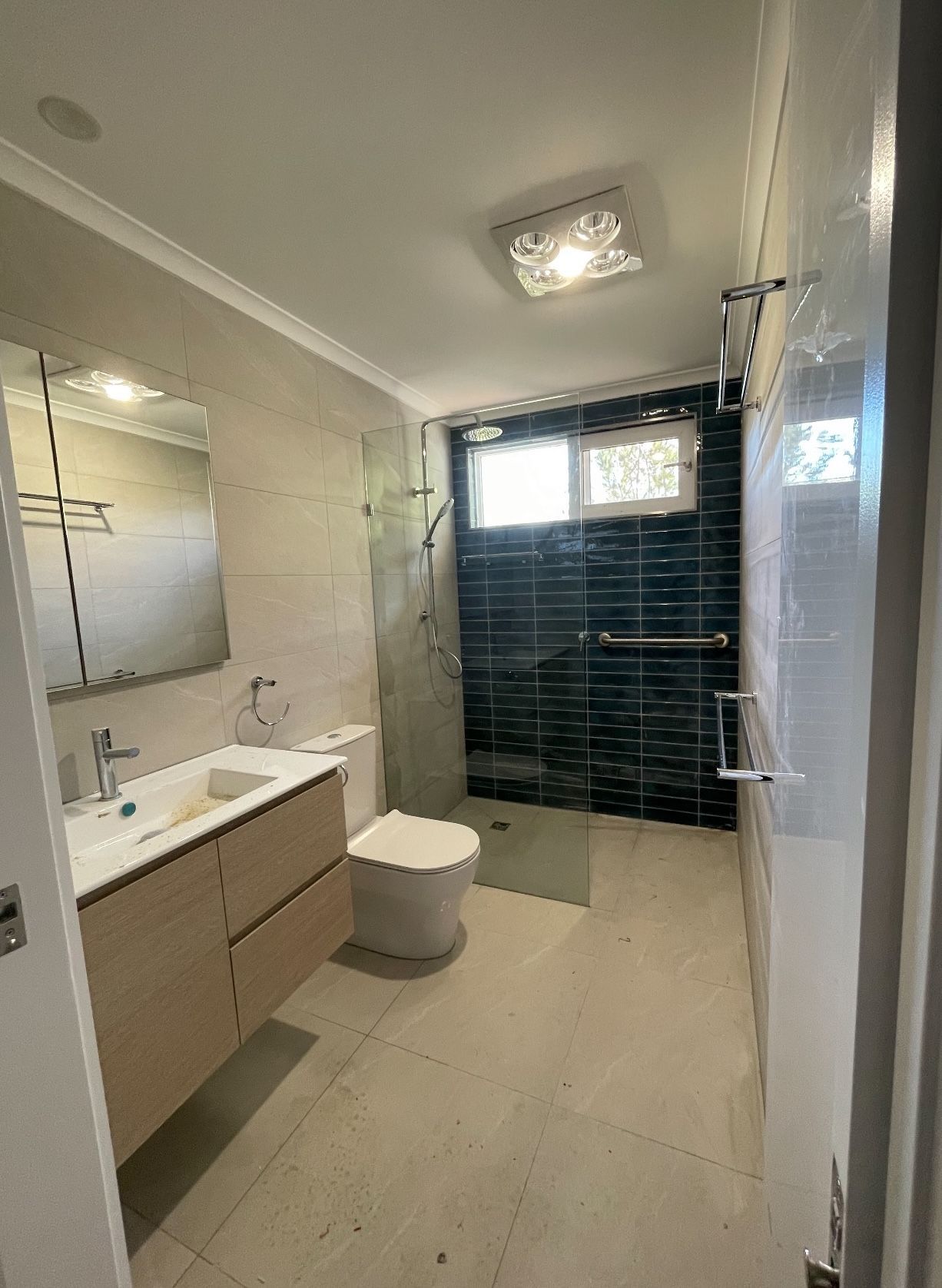 A bathroom with a toilet , sink , mirror and walk in shower.