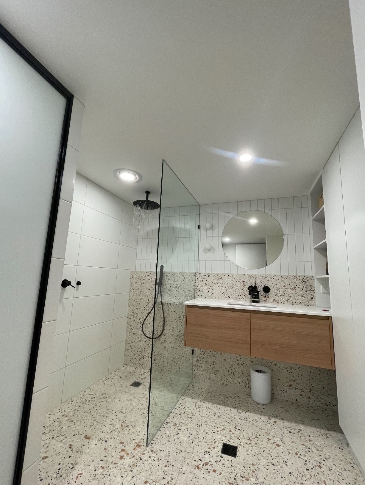 A bathroom with a walk in shower , sink and mirror.