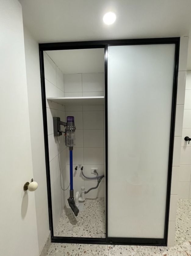 A vacuum cleaner is sitting in a closet with sliding glass doors.