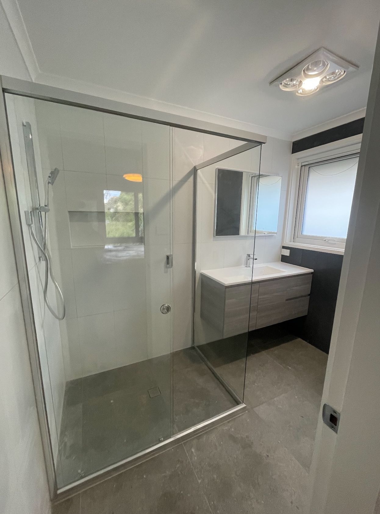 A bathroom with a walk in shower , sink and mirror.