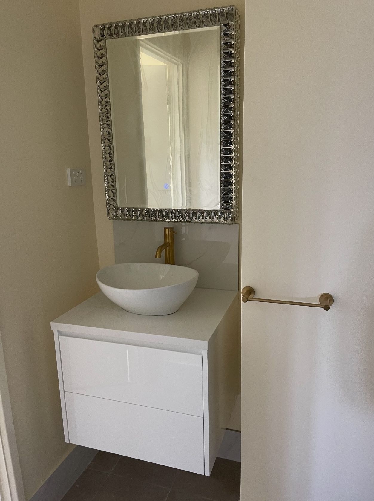 A bathroom with a sink , mirror and towel rack.